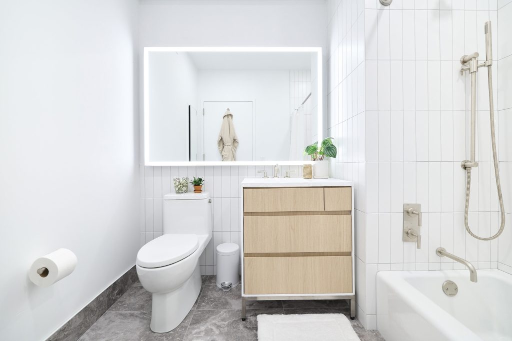 Bathroom at 499 President in Gowanus with a large mirror, single vanity, bathtub with shower and tile floors.